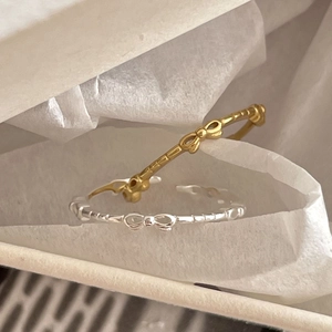 Minimalist 925 silver bow rings in gold and silver finish on soft white packaging