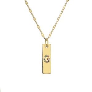 Detailed macro view of gold plated necklace with colorful rhinestone letter G pendant