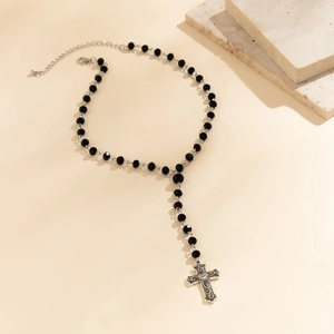 Detail of gothic rosary necklace featuring black faceted beads and silver cross pendant