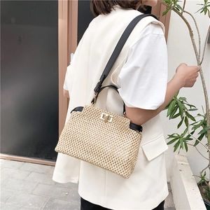Chic woven straw shoulder bag in beige with black straps and gold-toned metal buckles
