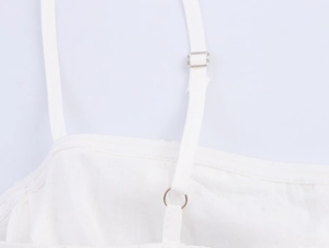 Detail of adjustable thin shoulder straps with metal sliders on a white midi dress