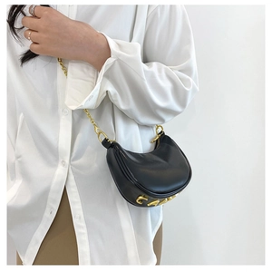 Close-up of black half-moon hobo bag featuring bold gold metal letters and chain strap