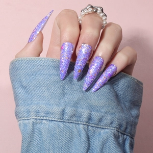 Detailed view of long stiletto press-on nails with purple glitter and sequins