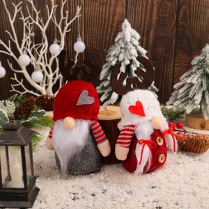 Christmas gnomes with reindeer antlers and knit hats in snowy festive table setting