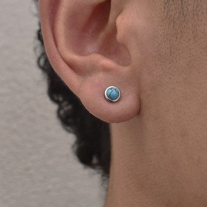 Minimalist turquoise stud earring for men with silver metal edge in a close-up ear view