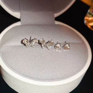 Macro shot of silver bow and heart stud earrings set with sparkling crystals in a box