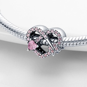 Detailed shot of silver heart charm with pink stones and arrow on snake chain bracelet