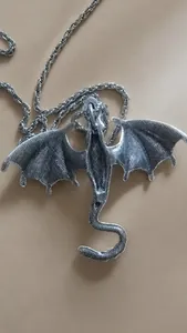 Detail of silver dragon pendant necklace featuring large wings and mesh back texture