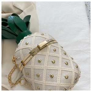 Detail of pineapple bag showing beige quilted texture and gold metal studs decoration