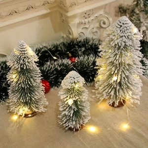 Three frosted mini Christmas trees with warm LED lights and rustic wooden bases