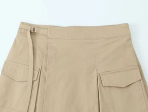 Detail of khaki cargo skirt showing D-ring belt and utility flap pocket with clean texture