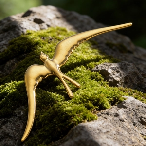 Détail d'une broche en forme d'hirondelle dorée avec finition métallique sur mousse