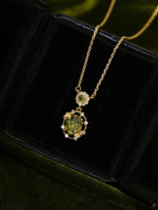 Macro shot of 18K gold plated vintage necklace with oval green emerald pendant on black velvet