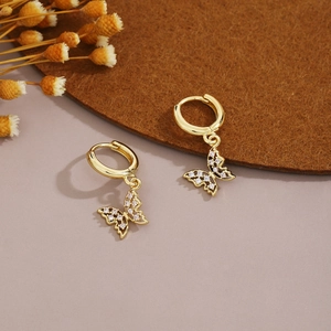Detailed close-up of gold butterfly hoop earrings with hollow wings and sparkling crystals