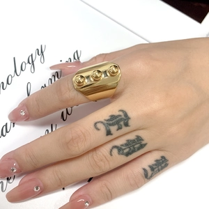 Detail of wide gold statement ring with three metallic spheres on an octagonal plate