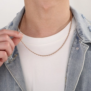 Detail of rose gold twisted rope chain necklace worn by a model on a white shirt