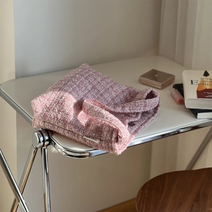 Sac à épaule en tweed rose avec étiquette tissée sur un bureau blanc ensoleillé