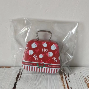 Close-up of a mini Christmas tin suitcase with Santa Claus patterns and metal handle