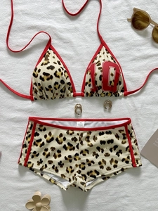 Two-piece leopard print bikini with red trim and halter top on white textured background