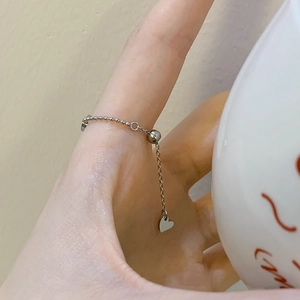 Adjustable silver chain ring with heart charm shown in a daily lifestyle hand setting