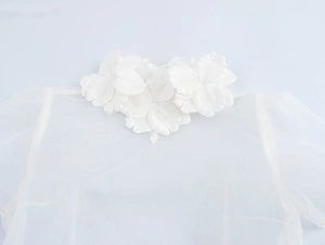 Close-up of elegant 3D white fabric flowers on a sheer organza women's blouse neckline