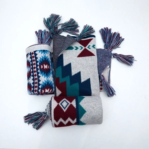 Close-up of ethnic knit shawl featuring geometric diamond patterns and colorful tassels