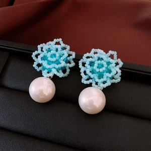 Detailed view of light blue beaded flower earrings with a large white imitation pearl drop