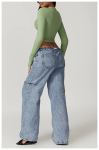 Rear view of an olive green slim fit yoga top paired with distressed wide leg jeans