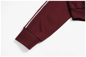 Detail of ribbed cuffs and white side stripes on burgundy windproof zip-up sweatshirt