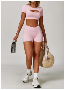 Rosafarbenes Yoga-Set mit gekreuztem Bund, Crop Top und Sporthose an einem Modell getragen