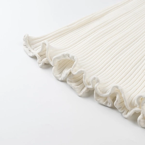 Detailed macro view of white ribbed knit fabric featuring delicate wavy lettuce edges