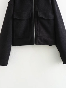 Detailed view of women's black wool jacket featuring dual front flap pockets and zip hem