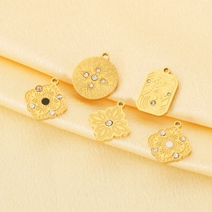 Detailed view of five vintage gold plated charms with micro inlay stones on orange silk