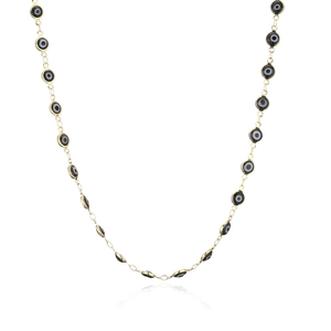 Detail of gold-plated chain necklace featuring black enamel evil eye beads on white background