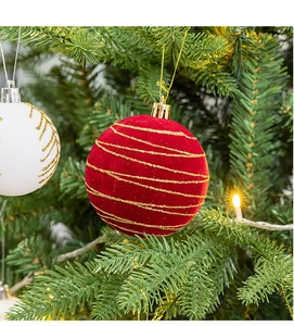 Close-up of a red velvet Christmas ball with gold glitter patterns on a tree branch