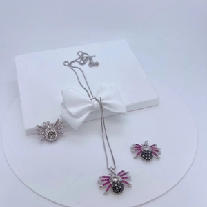 Macro shot of spider-shaped silver necklace and earrings with black and pink crystals