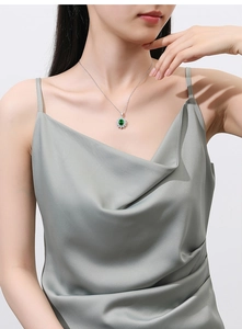 Detail of s925 silver necklace with green gemstone sunflower pendant on female model