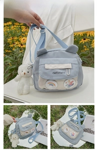 Detail view of light blue crossbody bag with bear ears, rainbow badge and plush charm
