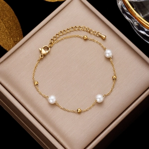 Golden stainless steel pearl bracelet displayed on elegant champagne silk jewelry box