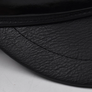 Close-up of black PU leather texture with detailed double stitching on the beret brim