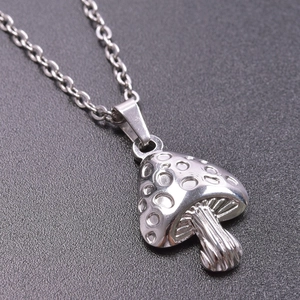 Macro shot of silver mushroom pendant necklace with circular textured details and thin chain