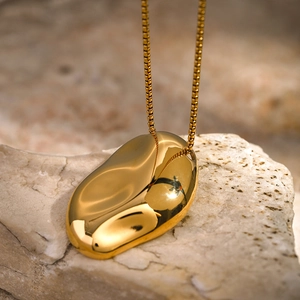 Minimalist 18k gold irregular pebble pendant on box chain over natural rock