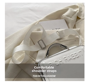 Close-up of the white tote bag handle and textured wide shoulder strap with metal buckle