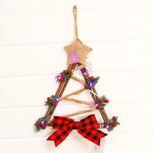 Detail of tree-shaped Christmas wood hanging with green pine, red berries and LED lights