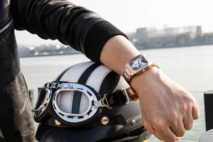 Close-up of rose gold square skeleton watch on wrist with biker style jacket