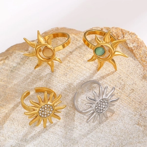 Close-up of gold and silver sunflower rings with cat-eye stones on natural rock base