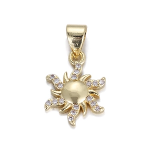 Détail d'un pendentif soleil doré avec strass transparents sur fond blanc pur