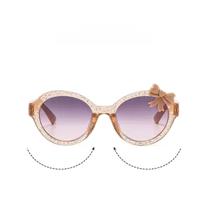 Detail of champagne glitter frames with bow decoration and gradient lenses on kids sunglasses