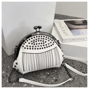 Detailed shot of a white shell bag with metallic studs, fringe chains, and clasp lock