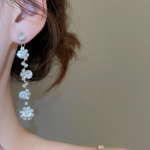 Close-up of sparkling tassel earrings with diamond accents on a model for a luxury look